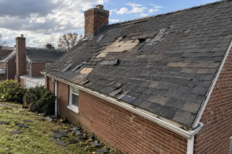 Lifted and missing asphalt shingles on a roof slope after a windstorm